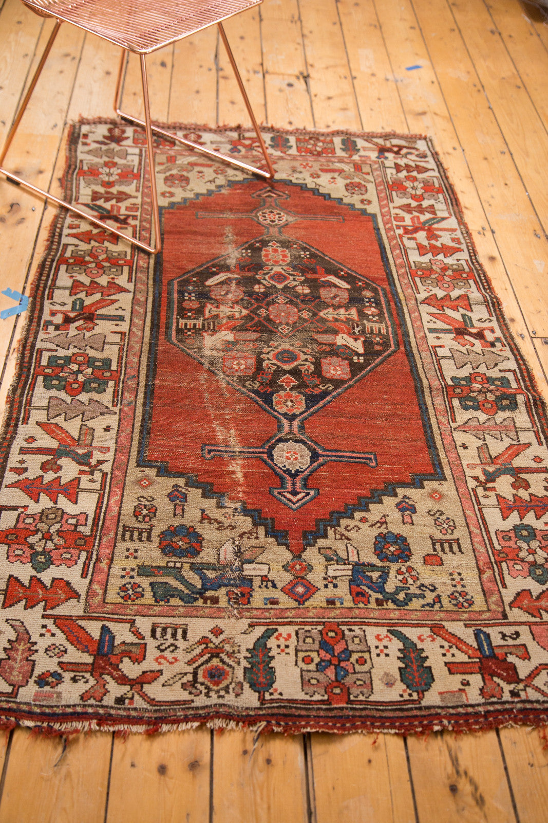 Distressed red Kurdish Hamadan rug showing geometric border and stylized birds.